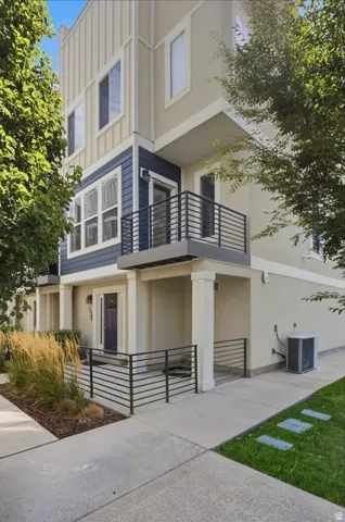 Contemporary exterior featuring multiple balconies, a covered entryway, horizontal metal railings, and varied siding materials