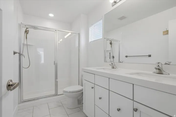 Dual vanity with undermount sinks, frameless mirror, white cabinetry, and brushed nickel hardware