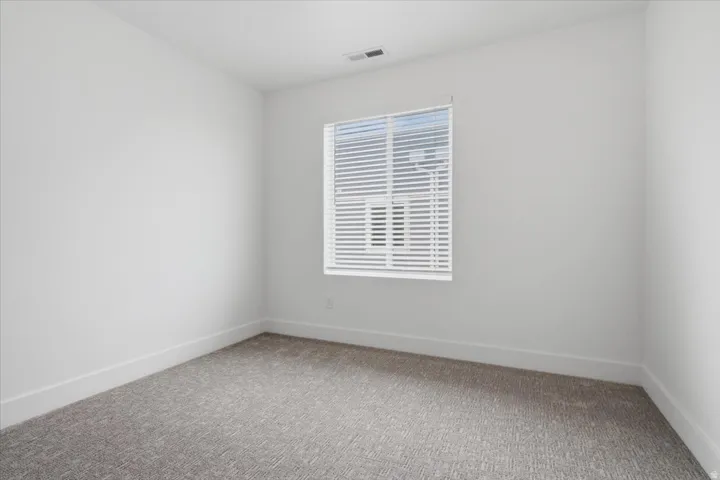 Neutral wall tones, gray carpet flooring, a window with white blinds, and white trim