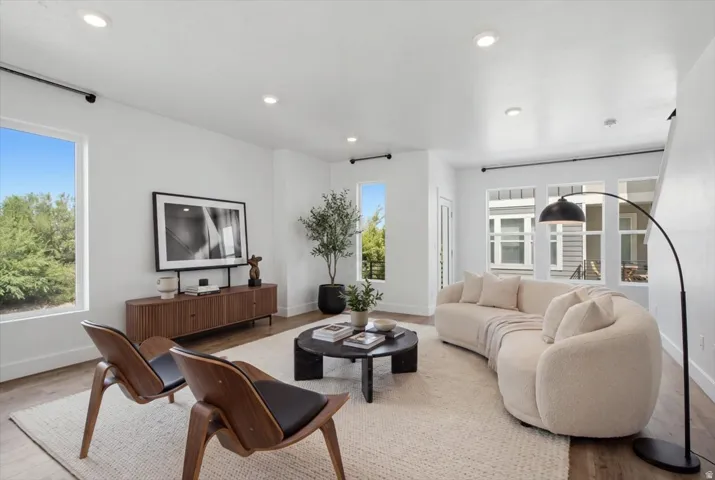 Recessed lighting illuminates an open-concept living space with wood-finish flooring