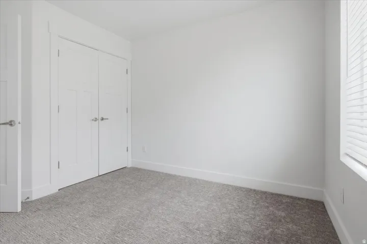White walls, neutral carpeting, and a double-door closet with satin nickel hardware
