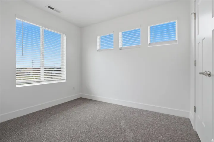 White walls and ceiling, gray patterned carpeting, recessed lighting, and multiple windows with white blinds