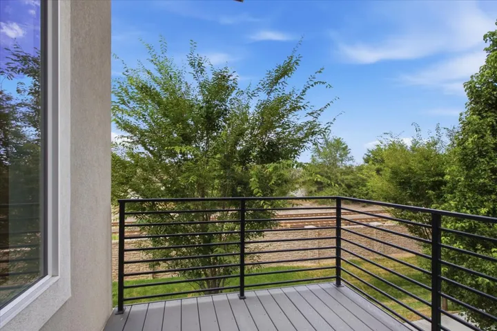Outdoor balcony with a horizontal black railing, composite decking, and exterior stucco finish