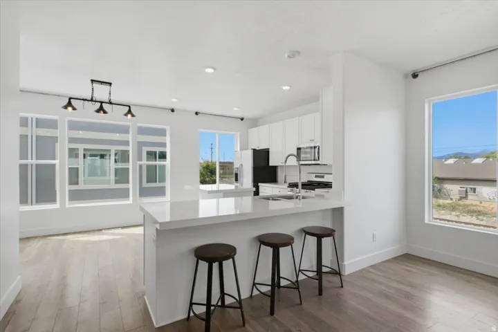 Open-concept living area with wood-finish flooring, recessed lighting, and expansive windows