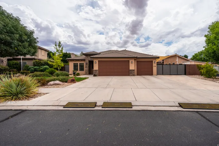 Single-story residence featuring a two-car garage, stone and stucco exterior, and a tiled roof