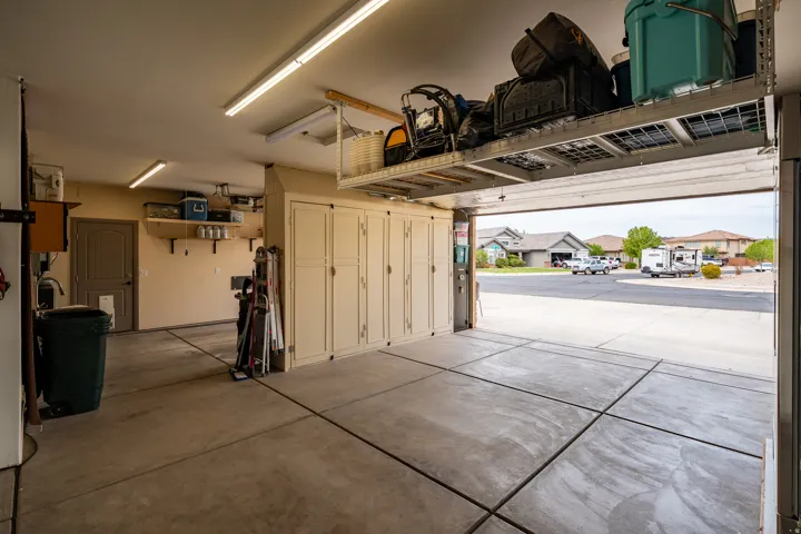 Attached garage featuring concrete flooring, built-in storage cabinetry, and overhead shelving