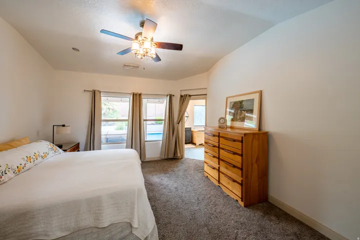 Vaulted ceiling with an attached ceiling fan, carpeted flooring, and multiple windows providing outdoor light