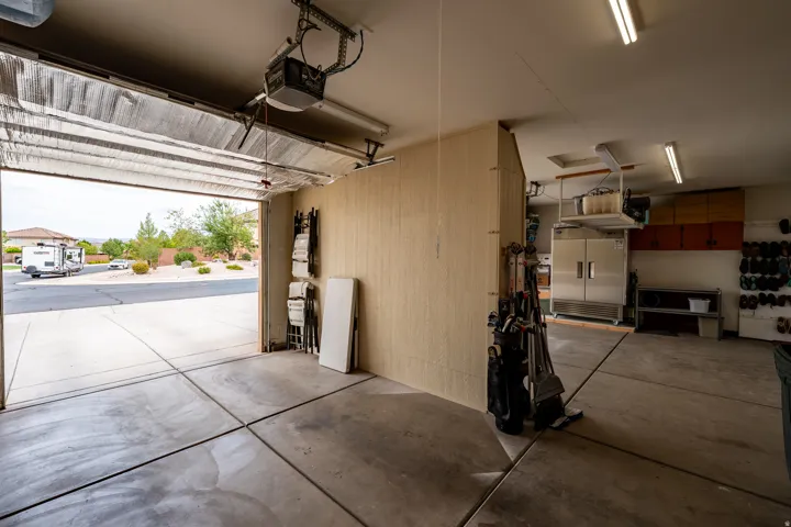 Concrete flooring garage with an automatic garage door opener, overhead lighting, and built-in storage solutions