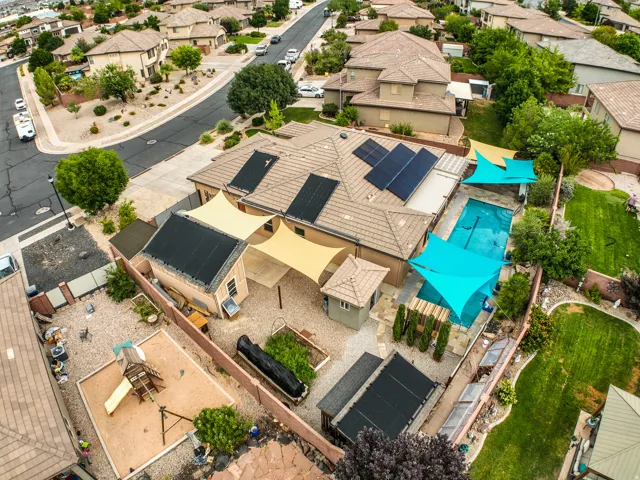 Residential property featuring a swimming pool, multiple shade structures, solar panels, and a detached outbuilding