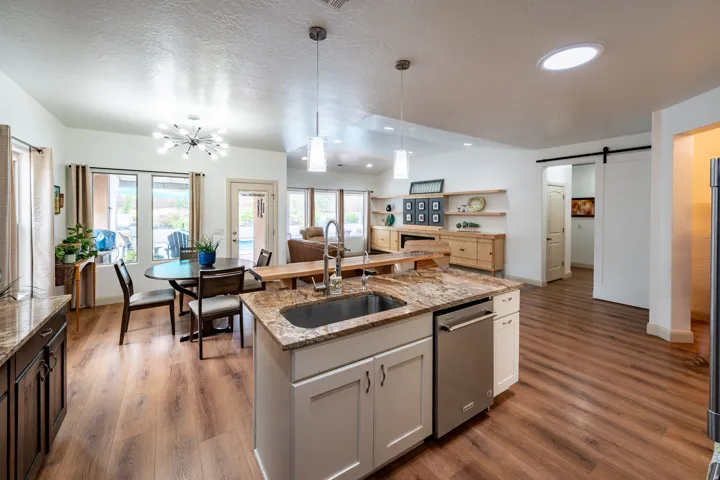 Kitchen island with a stainless steel sink, dual pendant lighting, and granite countertops