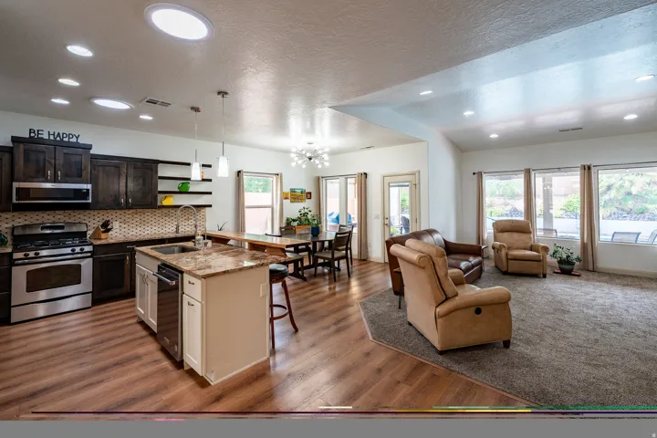 Open-concept living area with wood-finish flooring, recessed lighting, and skylights