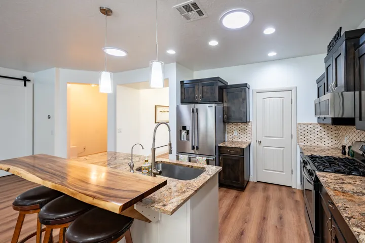Kitchen featuring wood-finish flooring, granite countertops, and dark-toned cabinetry