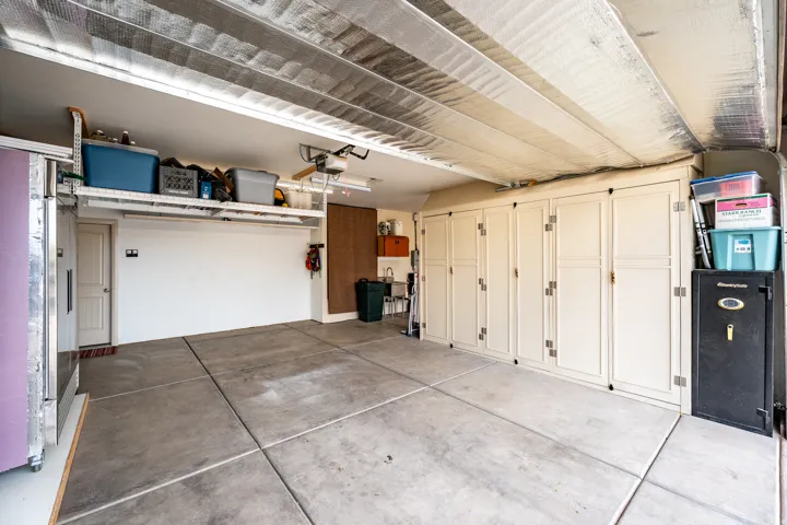 Concrete slab flooring, built-in cabinetry, overhead storage racks, and insulated ceiling