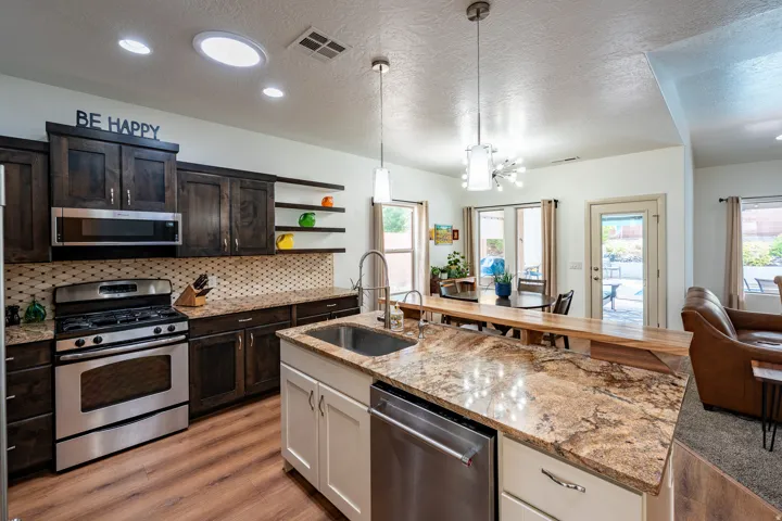 Kitchen featuring stainless steel appliances, dark wood cabinetry, granite countertops, and wood-finish flooring