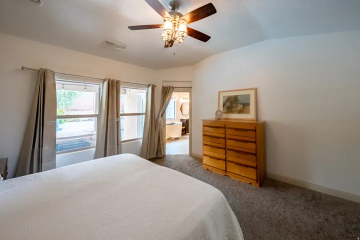 Carpeted flooring, vaulted ceiling, multi-pane windows, and a ceiling fan with integrated lighting