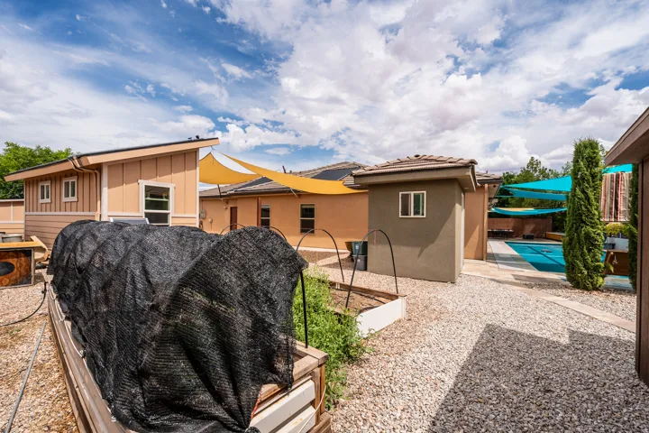 Expansive outdoor space featuring gravel ground cover, raised garden beds, a swimming pool, and a dedicated pool house