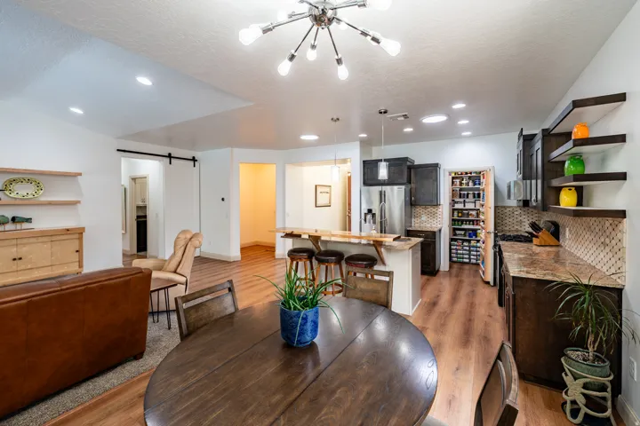 Wood-finish flooring throughout, kitchen with dark cabinetry, stainless steel appliances, and a pantry with built-in shelving