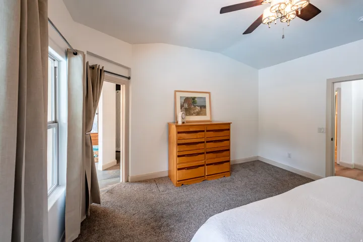 Vaulted ceiling, ceiling fan with integrated lighting, carpeted flooring, and white walls