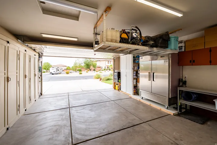Concrete flooring, built-in cabinetry, overhead storage racks, stainless steel commercial-style refrigeration, wall-mounted storage cabinets