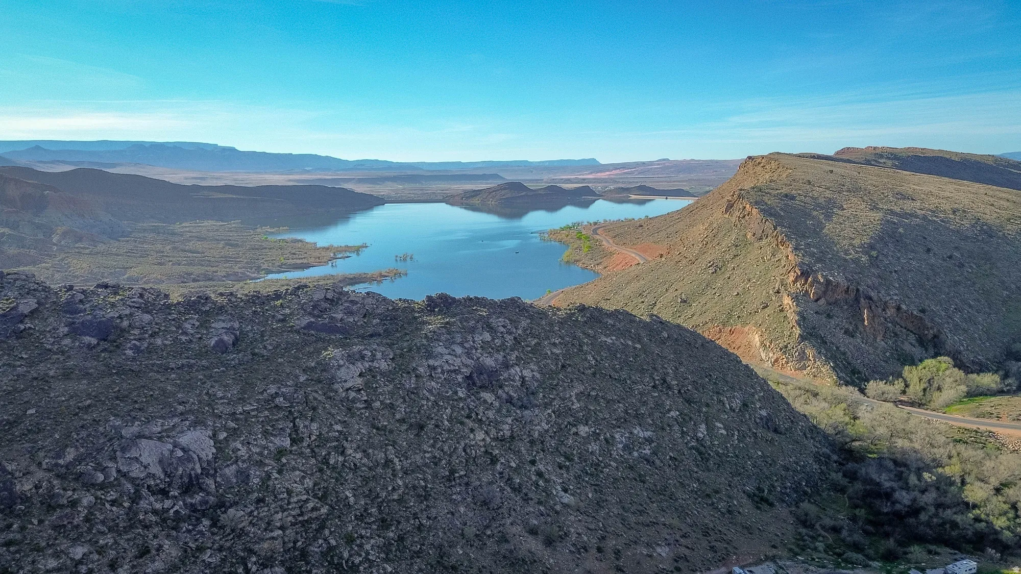 Expansive body of water surrounded by mountainous terrain and a clear sky