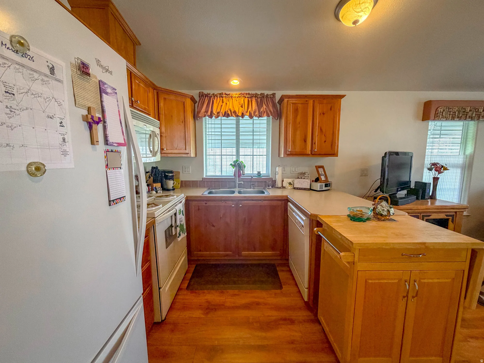 Kitchen featuring wood-finish flooring, wood cabinetry, a double basin sink, and a portable wood island