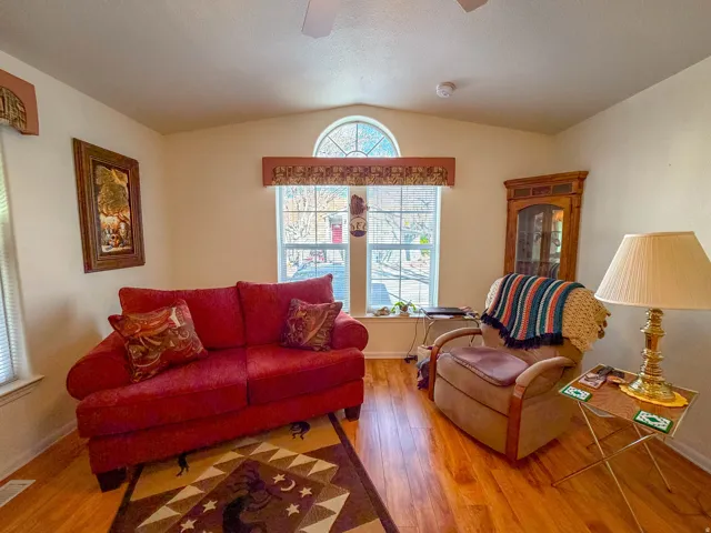 Wood-finish flooring throughout, vaulted ceiling, arched transom window, and a built-in corner cabinet with glass-front doors