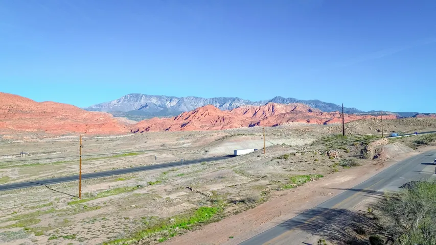 Expansive desert landscape featuring red rock formations and distant mountains