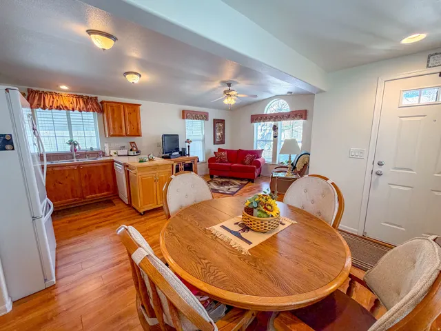 Wood-finish flooring throughout, kitchen with wood cabinetry and stainless steel sink, recessed lighting and ceiling fan, and a front entry door with decorative glass