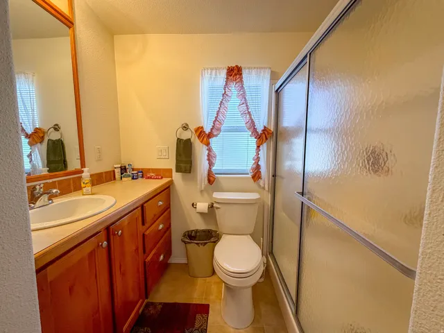 Vanity with wood-finish cabinetry, integrated sink, and an expansive mirror