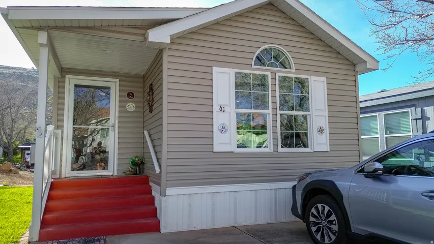 Siding exterior with decorative shutters, covered porch, and arched transom window