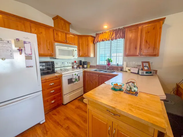 Kitchen featuring wood-finish cabinetry, white appliances, and a double-basin sink