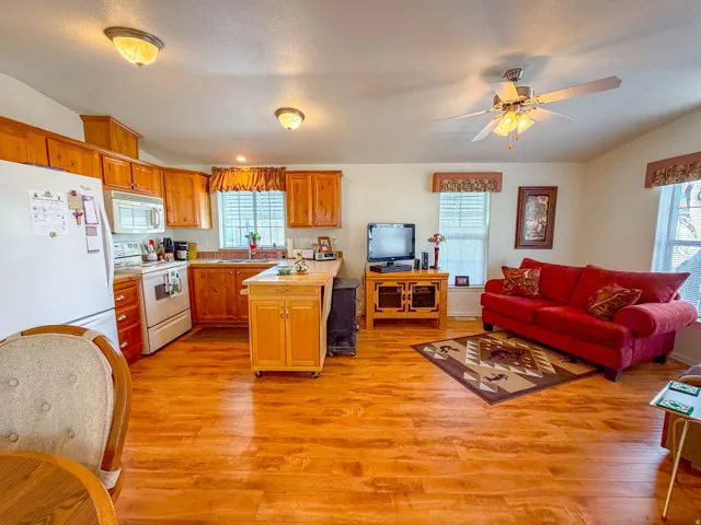 Open-concept living area with wood-finish flooring, recessed lighting, and a ceiling fan