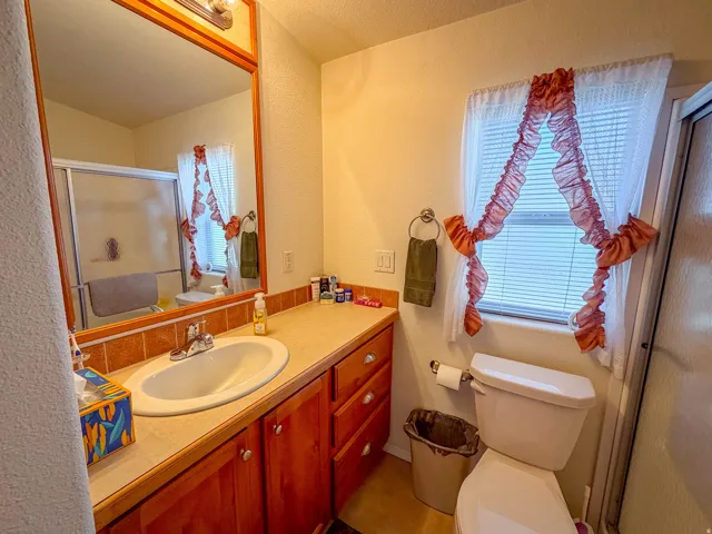 Wood-finish vanity with an integrated sink, tile backsplash, and framed mirror with overhead lighting