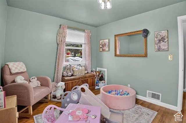 Wood-finish flooring, a window with blinds, and light green painted walls