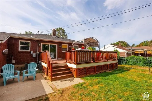 Brick exterior with a wooden deck, sliding glass door, and a concrete patio
