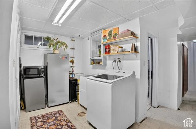 Dedicated laundry area with a top-load washing machine, wall-mounted shelving, and a window