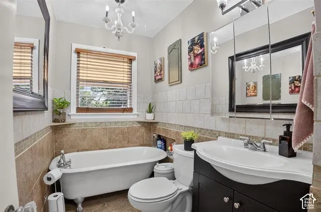 Spa-inspired master bathroom featuring a freestanding soaking tub, dual vanity with black cabinetry and white vessel sinks, subway tile surround, brushed nickel fixtures, and a large framed mirror