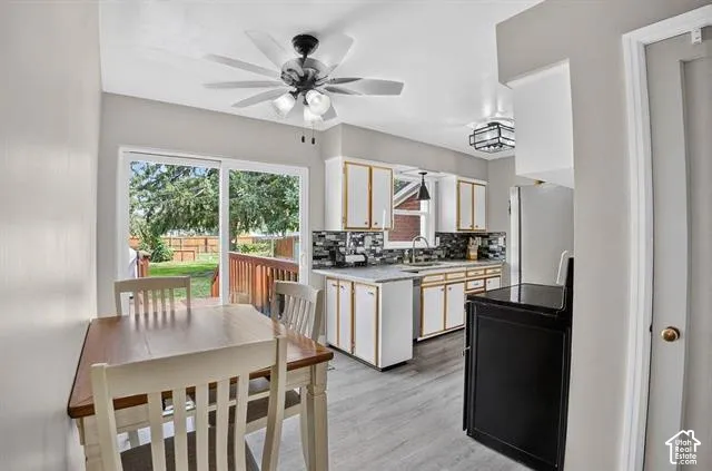 Kitchen featuring white cabinetry, a tile backsplash, light countertops, wood-finish flooring, and a sliding glass door to the exterior deck