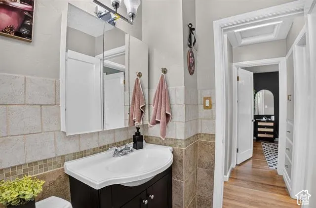 Bathroom featuring a vanity with integrated sink, wall-mounted medicine cabinet with mirror, and a two-tone tiled wall
