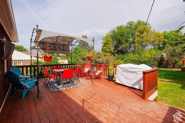 Expansive wood deck with a privacy railing and pergola structure, overlooking a substantial grassy area