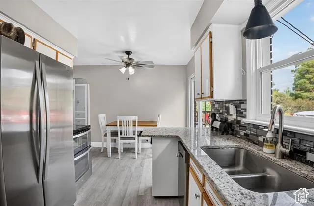 Kitchen featuring stainless steel appliances, wood-finish flooring, white cabinetry, a dual basin sink, and granite countertops