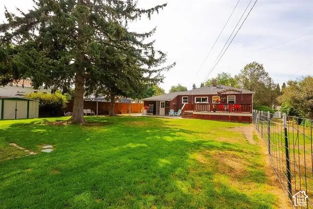 Expansive lawn with mature trees, a multi-level wood deck, and a detached storage shed
