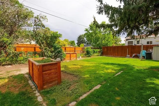 Spacious backyard featuring a mature landscaped setting with lush lawn, established trees, and raised garden planter