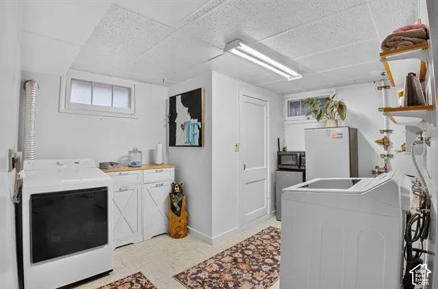 White cabinetry with wood-finish countertops, built-in shelving, and a drop ceiling with fluorescent lighting