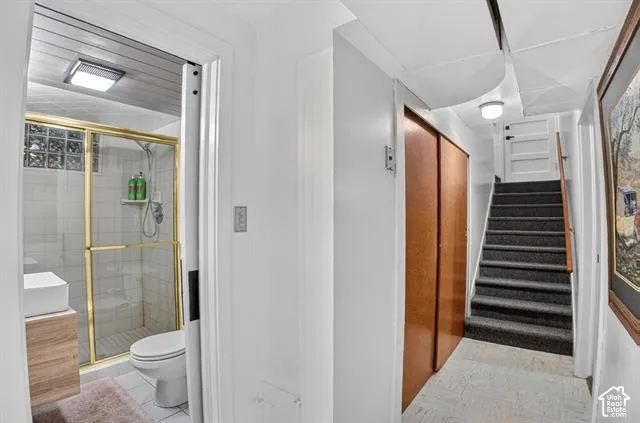 Bathroom featuring a glass-enclosed shower with gold-tone framing and a wood-finish vanity