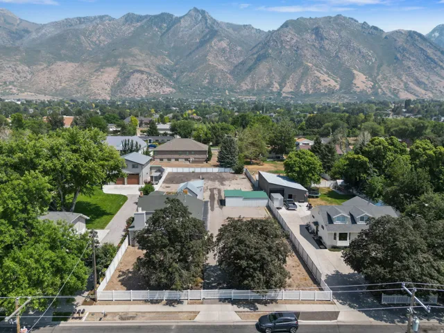 Expansive property featuring multiple structures, a paved drive, and mature trees, all set against a prominent mountain backdrop