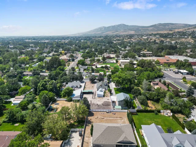 Expansive lot featuring a grass lawn, mature trees, and mountain scenery