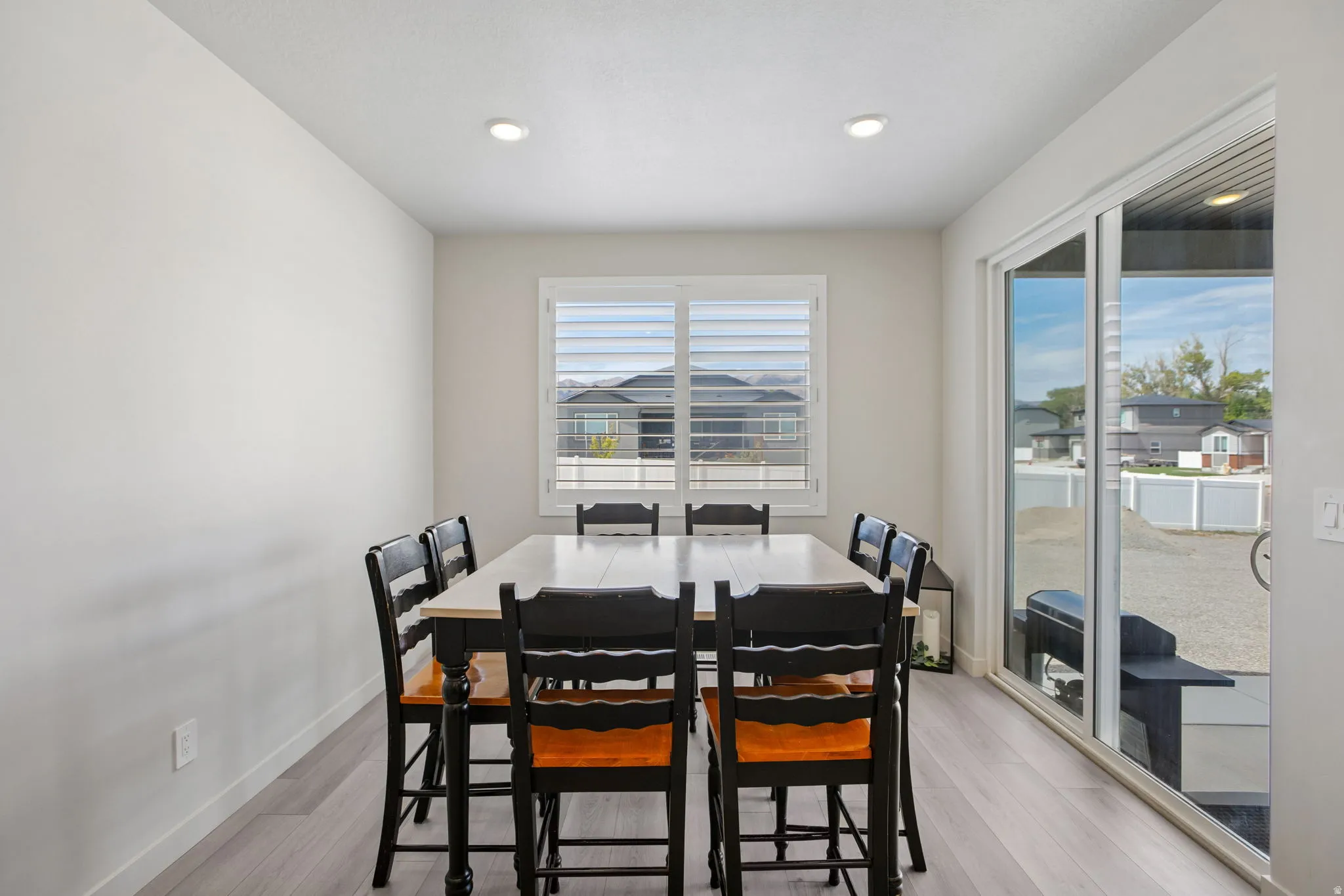 Recessed lighting, light wood-finish flooring, white plantation shutters, and sliding glass door