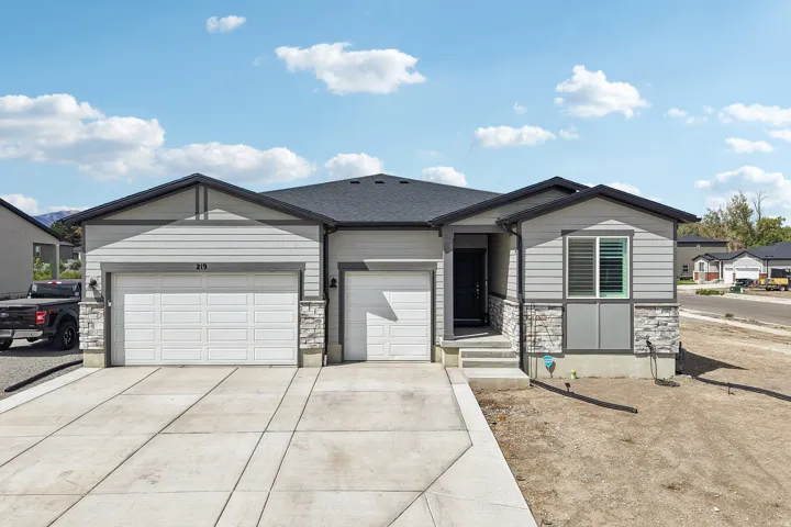 Contemporary exterior with light gray siding, dark trim, stone accents, and a two-car garage