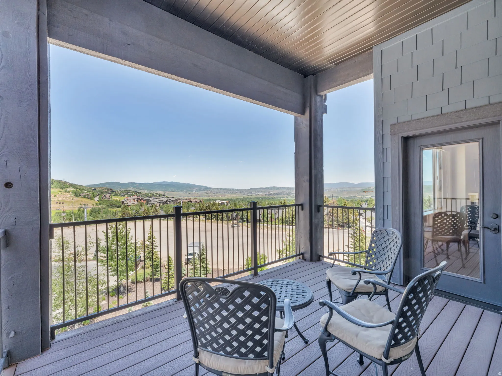 Covered balcony featuring composite decking, robust structural beams, and a metal railing